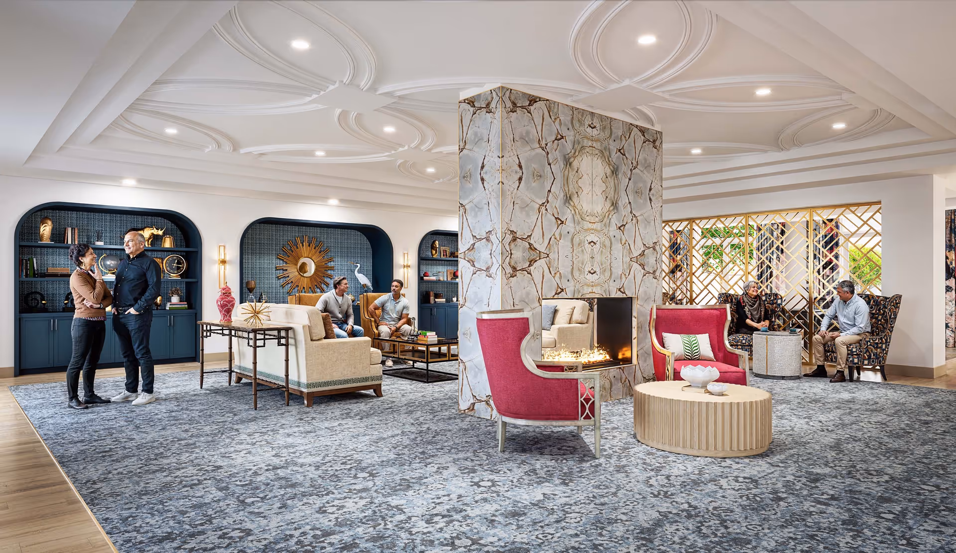 Spacious, well-lit lounge with a central stone fireplace, multiple seating areas, decorative shelving and several people conversing.