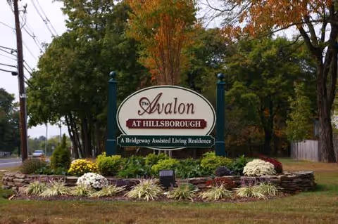 Front exterior sign for Avalon at Hillsborough with manicured beds and trees