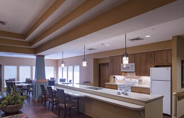 Open communal dining and kitchen area with a long island, pendant lights, and multiple tables and chairs.