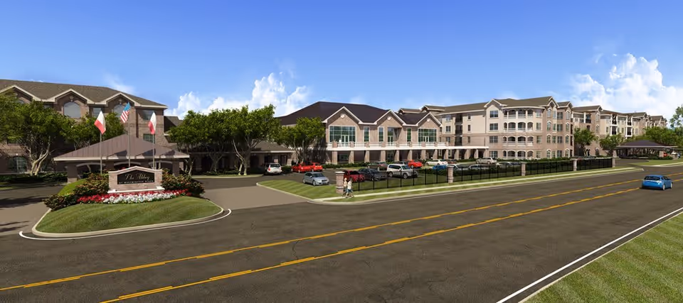 Exterior view of The Abbey at Westminster Plaza senior living facility showing a large multi-story building with multiple windows, a landscaped entrance with flags, parked cars, and a road in the foreground under a blue sky with clouds.