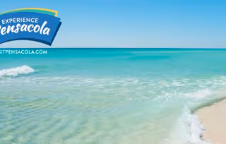 Turquoise ocean waves gently lapping a sandy beach under a clear blue sky with an 'Experience Pensacola' logo in the corner.