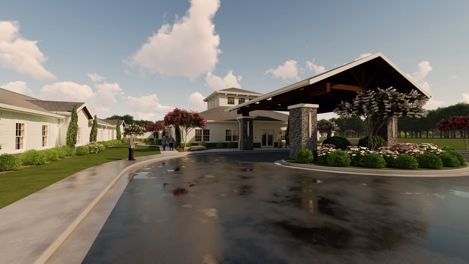 Front entrance of a senior living facility with a covered porte-cochere, circular driveway, landscaped beds and a few people near the walkway.