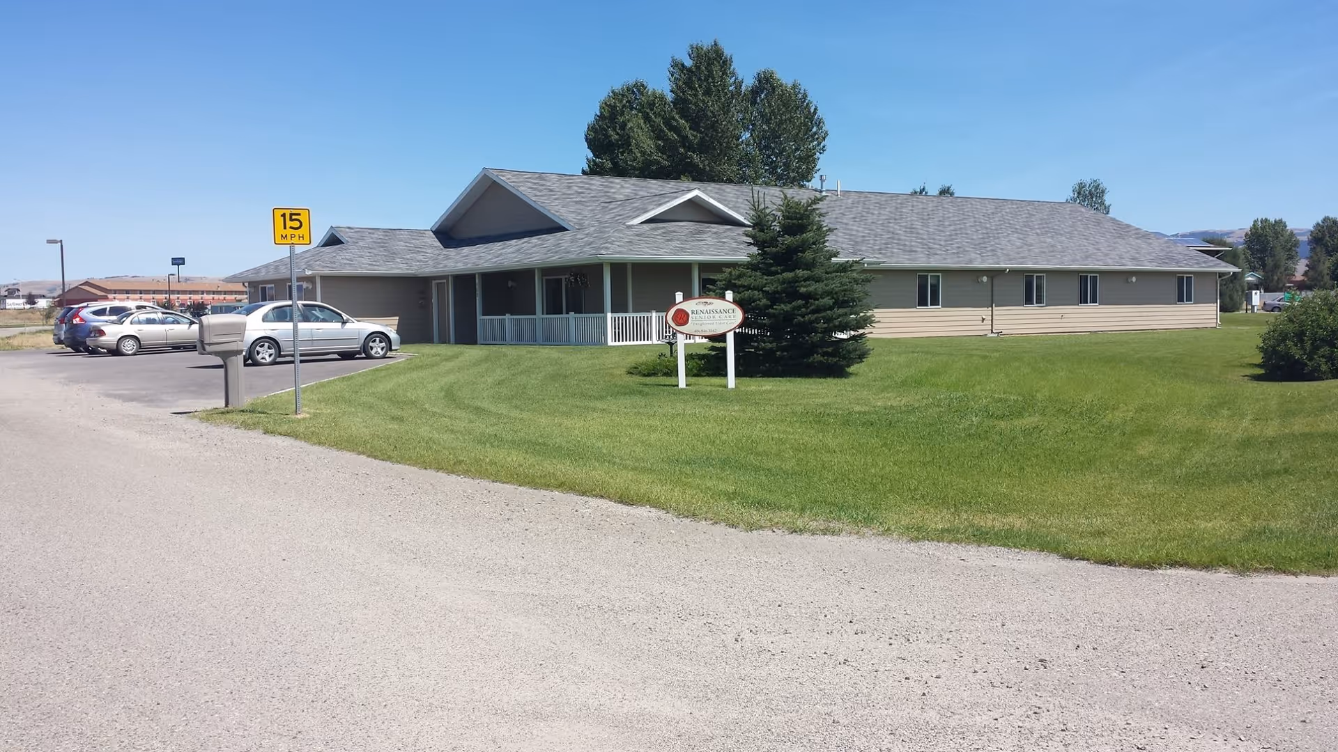 Single-story Renaissance Senior Care building with a front lawn, parking area, and entrance sign under a clear blue sky.