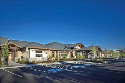 Single-story senior living facility with parking and handicap spaces in a sunny lot.