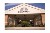 Covered front entrance of a brick building with a triangular pediment reading "OAKWOOD".