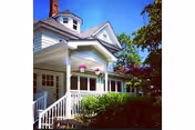 White front porch and railing of a house-style senior living facility with plants.