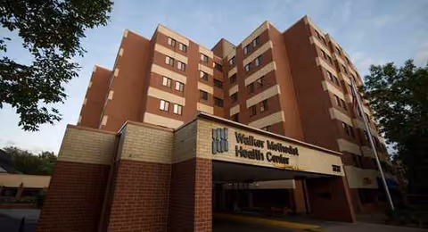Multi-story brick health center exterior with entrance canopy and front signage.