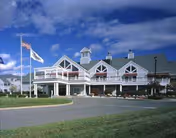 Seabury Active Life Plan Community building with flags, curved driveway, and blue sky.