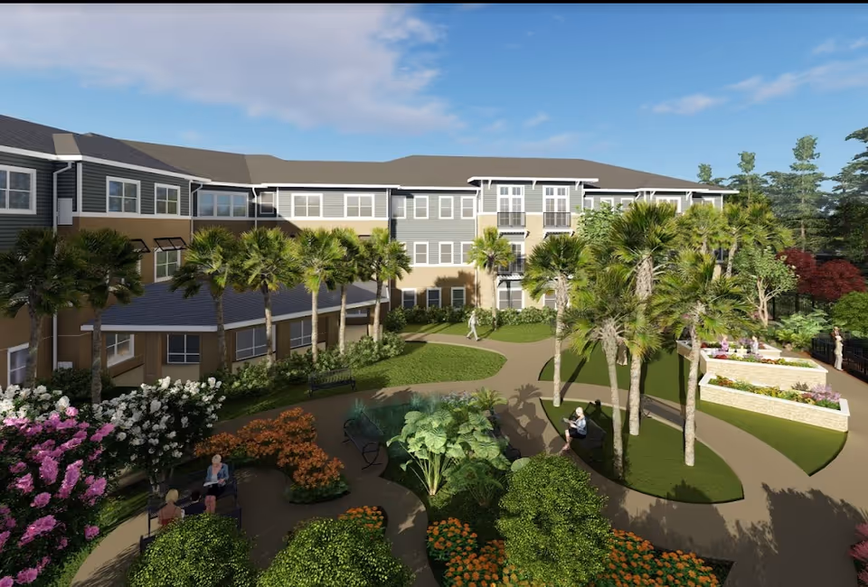 Outdoor garden area at HarborChase of Mandarin with walking paths, palm trees, flowering plants, benches, and a few people enjoying the space near a three-story residential building under a partly cloudy sky.