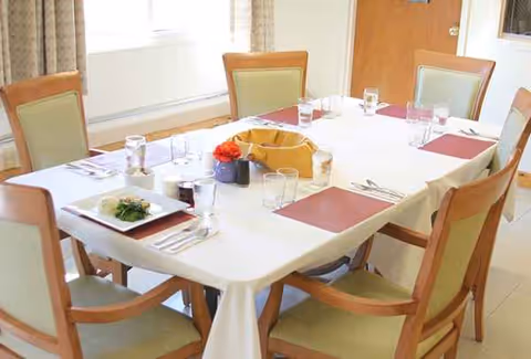 A dining room with a large table, chairs, and table settings for a meal.