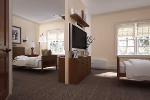 Bright shared bedroom with two single beds separated by a partial wall featuring a TV and dresser, and windows letting in daylight.
