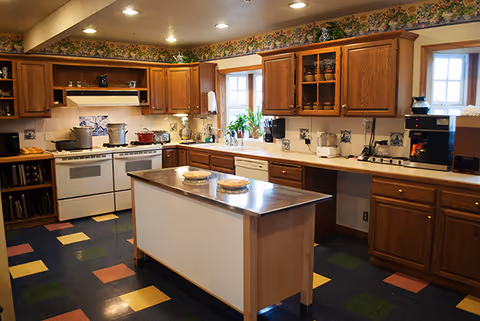 Spacious kitchen with wooden cabinets, a central island, stove and sink, and a colorful checkered floor.