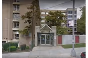 Entrance to Margaret Tietz Nursing and Rehabilitation Center with glass doors, trees, and sidewalk.