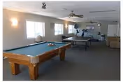 Recreation/common room with a pool table, ping-pong table, exercise equipment and seating under ceiling fans.