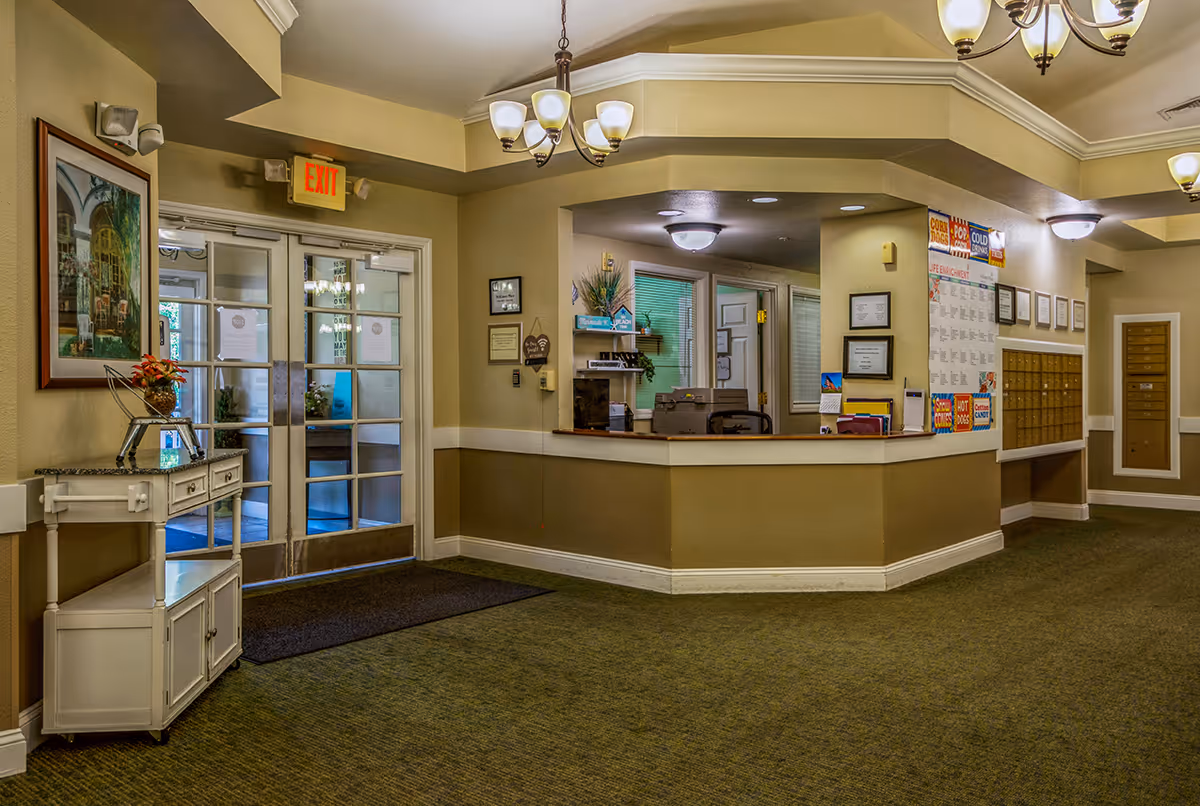 Reception lobby with a front desk, mail slots, and double glass entry doors under an exit sign.
