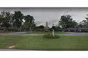 Front of Regal Heights Healthcare with manicured lawn, trees, and central statue.