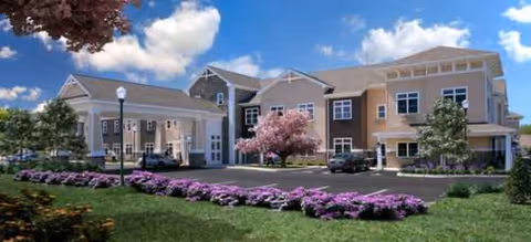 Front exterior view of Brookdale Centre of New England with parking and blooming trees.