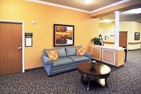 Yellow-walled lobby with a blue sofa, round coffee table, and reception desk.