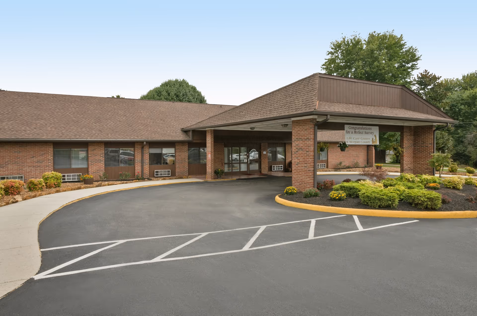 Exterior view of Life Care Center of Morgan County, a single-story brick facility with a covered entrance and landscaped surroundings.