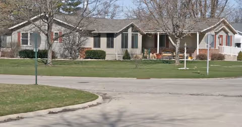 Single-story retirement community buildings with green lawns along a quiet residential street.