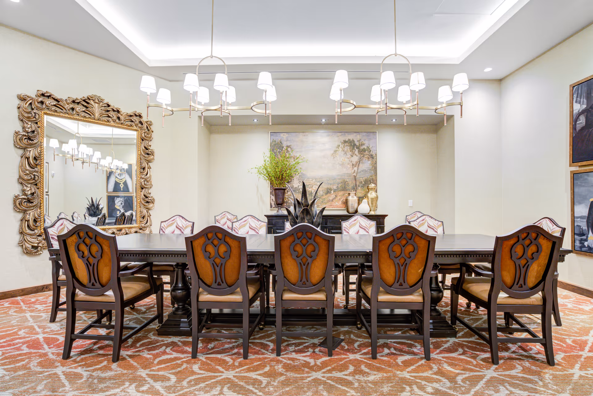 Formal dining room with a long wooden table surrounded by ornate chairs, chandeliers, a large decorative mirror, and artwork.
