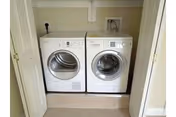Front-loading washer and dryer side-by-side inside a small closet with bi-fold doors.