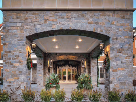 Stone entrance with arched portico, hanging lanterns, and landscaped approach.