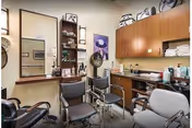 A small salon-style room with several styling chairs, mirrors, cabinets, and hair-care supplies.