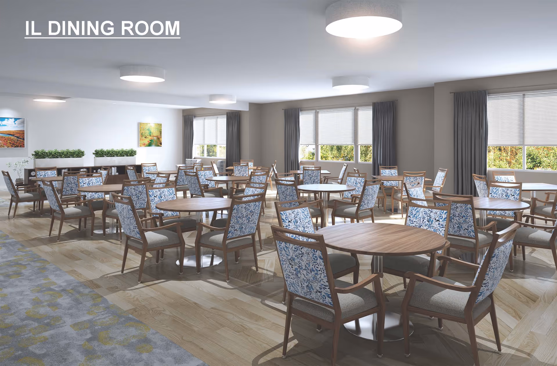 A spacious and well-lit dining room with multiple round wooden tables surrounded by chairs featuring blue floral patterned backs and gray cushions. The room has large windows with gray curtains allowing natural light to enter, light wood flooring, and modern ceiling lights. There are paintings and plants on the far wall.