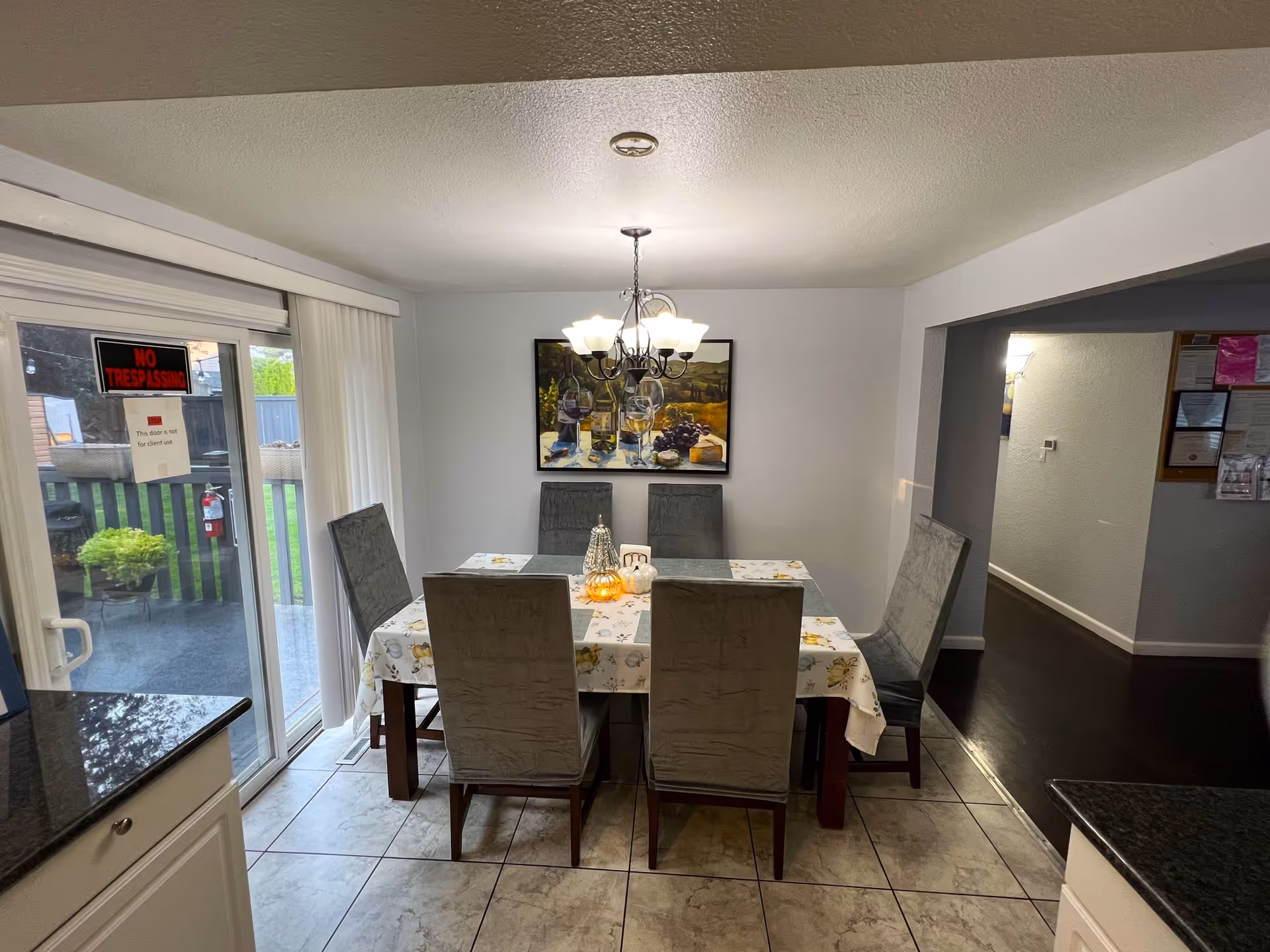 Dining room with a six-seat table under a chandelier and a sliding glass door leading to a patio.