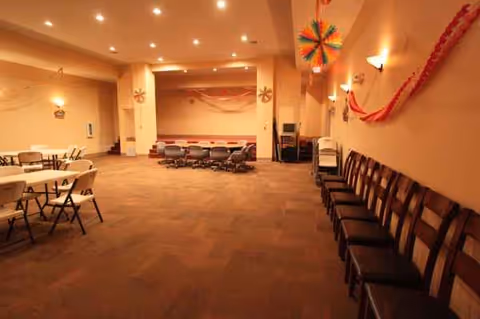 Spacious indoor event room with rows of chairs and festive decorations.