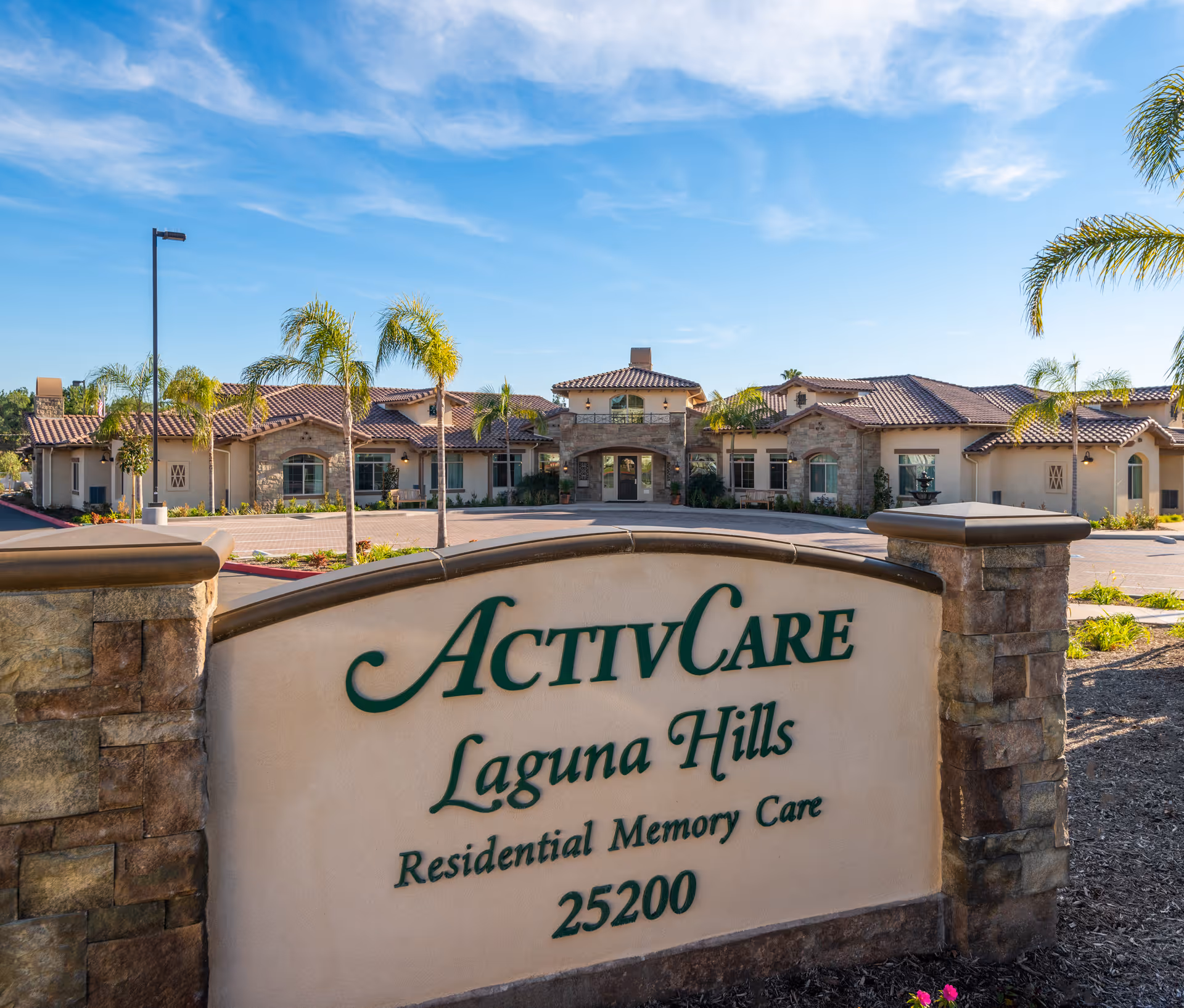 Front entrance and facade of ActivCare Laguna Hills residential memory care facility with the facility sign and landscaping in the foreground.