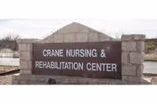 Stone sign for Crane Nursing & Rehabilitation Center displayed outdoors with a clear sky and some vegetation in the background.