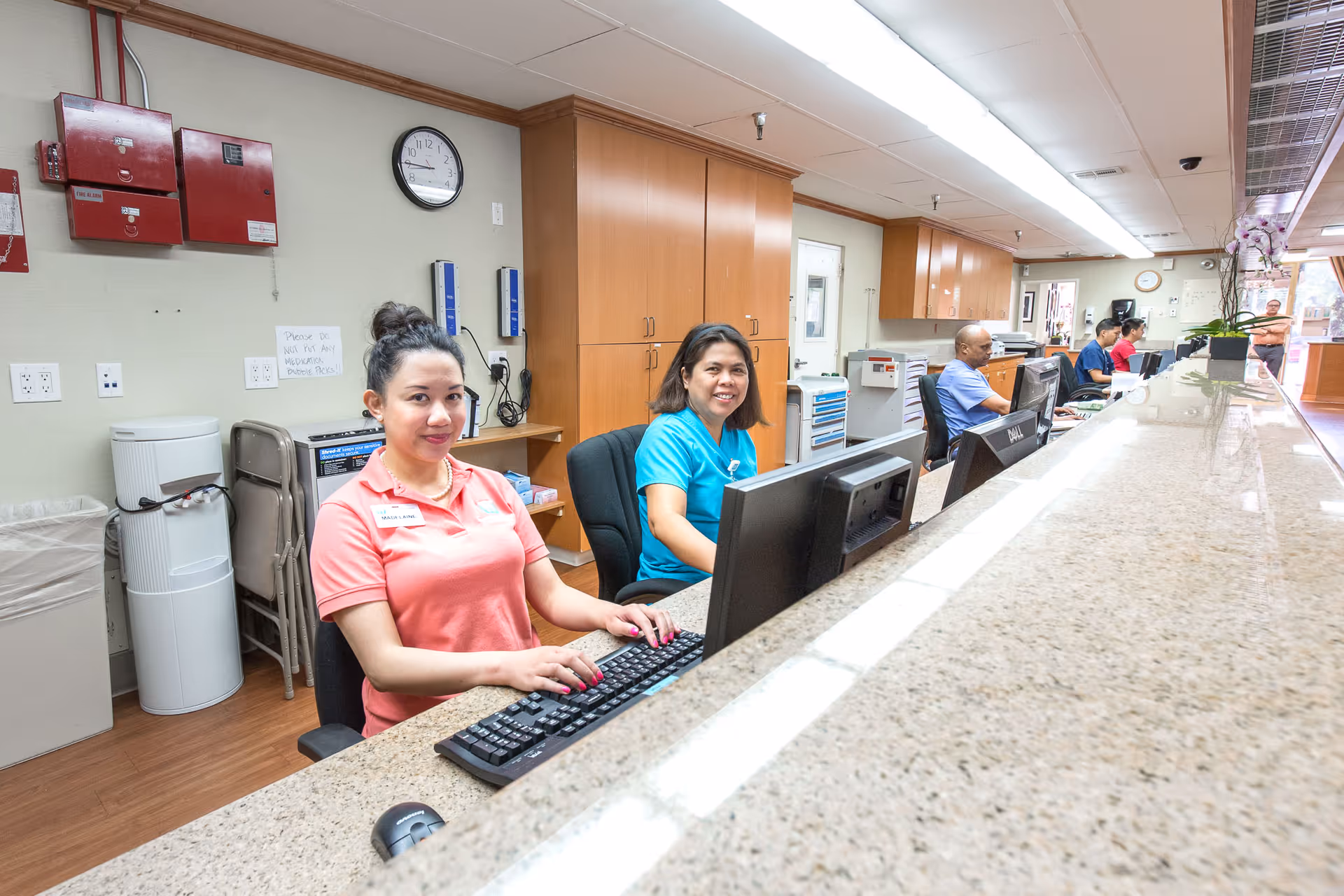 Reception desk inside a senior living facility with staff seated at computers smiling.