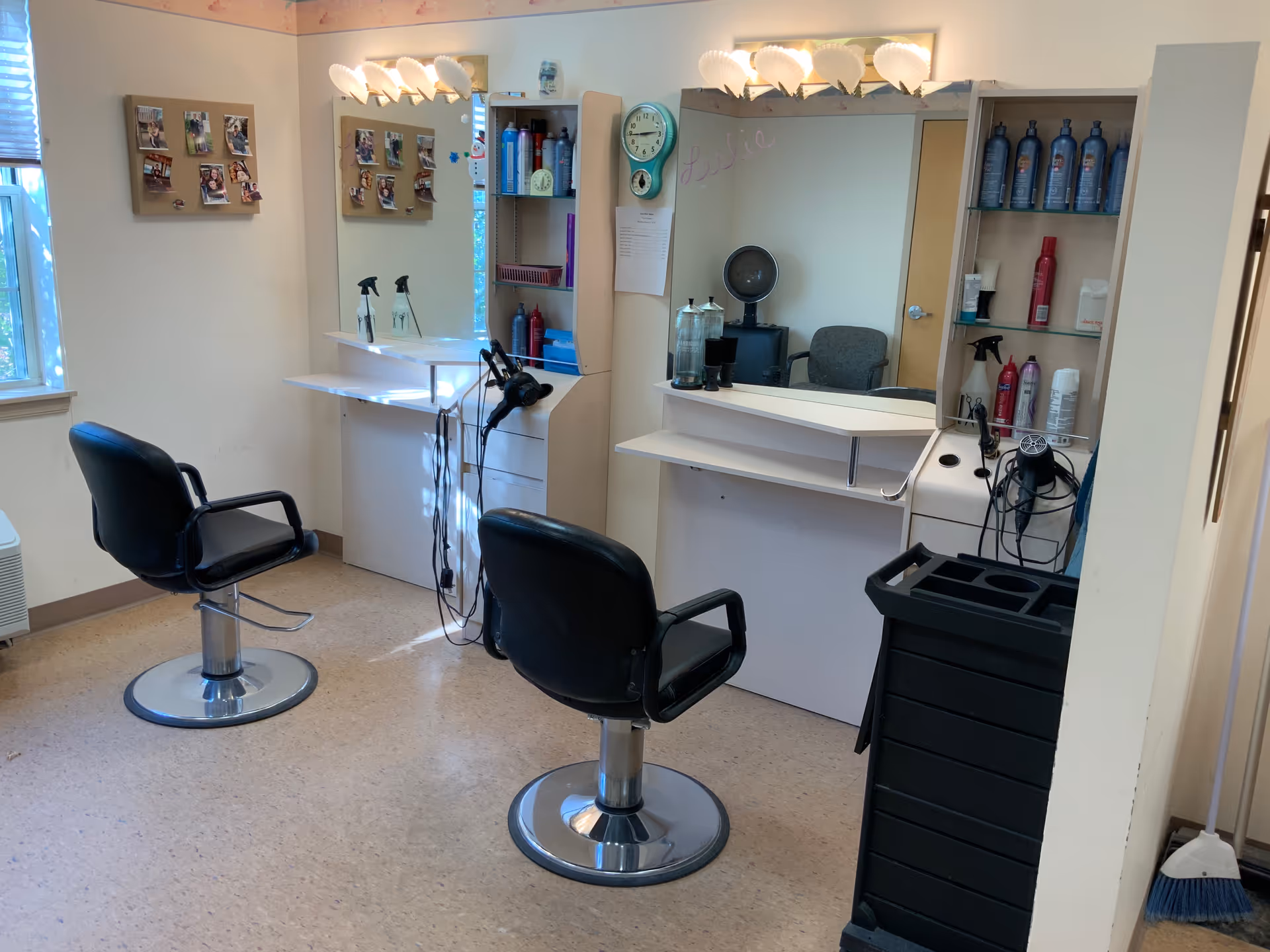 Interior salon area with two styling chairs facing mirrors and shelves stocked with hair products.