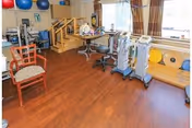 Interior rehab/therapy room with exercise equipment, parallel bars, chairs and large windows.