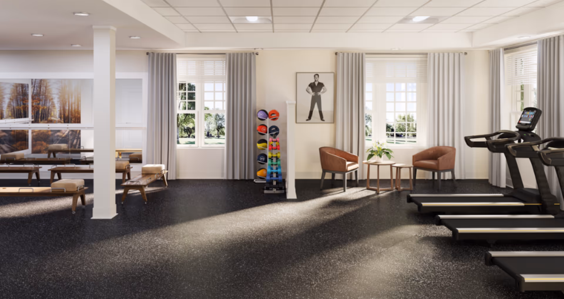 Bright interior fitness room with treadmills, exercise benches, a rack of weights, and seating by windows.