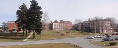 Exterior view of Jackie Withrow Hospital campus with brick buildings, trees, and a parking lot.