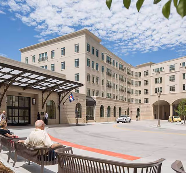 Exterior view of Balfour at Riverfront Park building with entrances, benches, cars, and pedestrians.