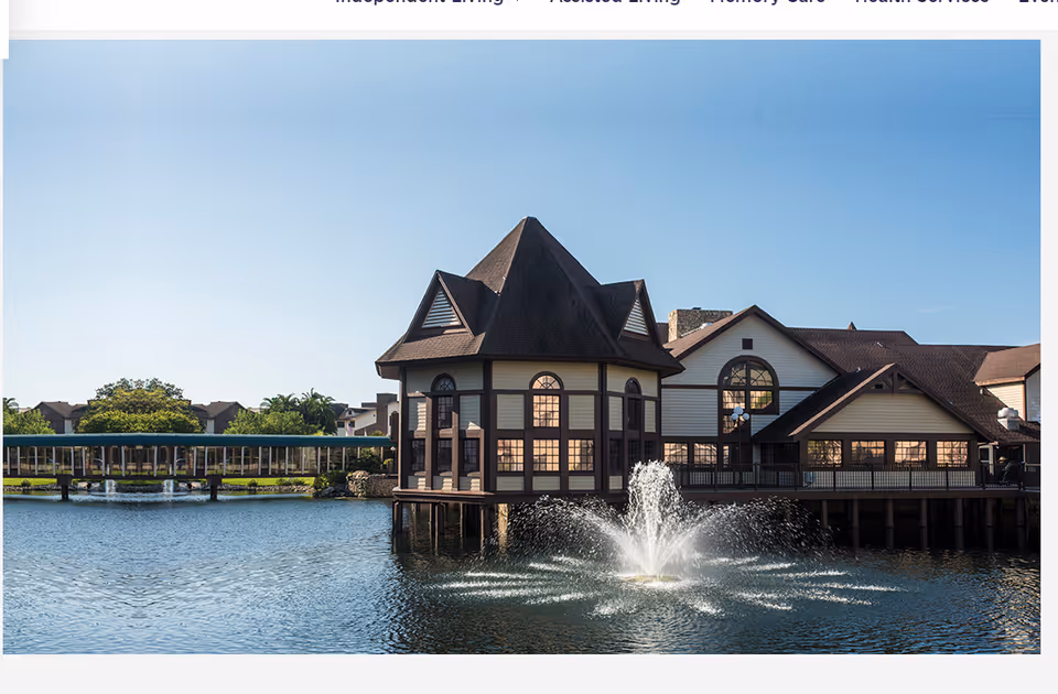Exterior view of The Inn at Freedom Village showing lake, fountain, and connected buildings.