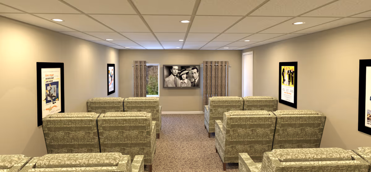 A small theater room with three rows of beige patterned armchairs facing a wall-mounted black and white movie screen. The walls are light beige with framed vintage movie posters on each side. Two small windows with curtains flank the screen at the front of the room. The ceiling has recessed lighting and a grid pattern.