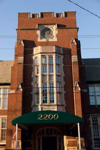 Brick building facade of The Lorelton with a clock tower and green entrance awning.