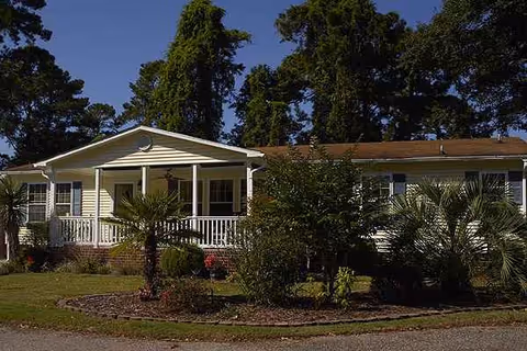 Single-story senior living facility front with a covered porch and landscaped yard.