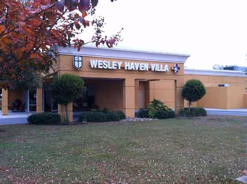 Exterior view of Wesley Haven Villa entrance with sign and landscaped lawn.