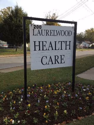 Outdoor sign for Laurelwood Health Care in front yard with colorful flowers.