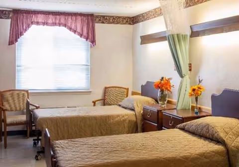 Two single beds with matching quilts, nightstands, and chairs in a bright, furnished bedroom.