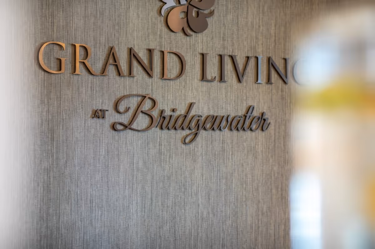 Close-up view of a textured wall with decorative wooden letters spelling out 'GRAND LIVING AT Bridgewater'.