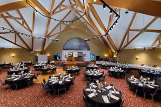 Interior banquet hall at Easterseals Rehabilitation Center with round tables and a stage.