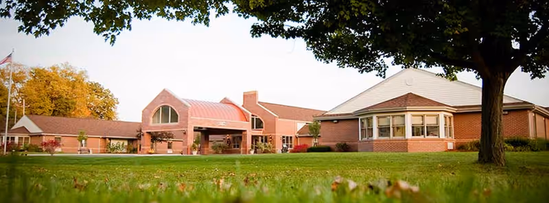 Front exterior of Crawford County Care Center showing a single-story brick building with a covered entrance, green lawn, and trees.