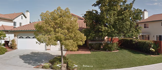 Residential-style senior living facility front yard with trees, lawn, and driveway.